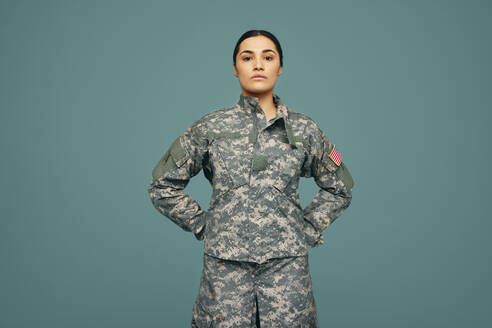 Junger amerikanischer Armeesoldat vor einem Studiohintergrund. Tapfere junge Soldatin in tarnfarbener Militäruniform mit der Flagge der Vereinigten Staaten von Amerika. - JLPPF01233