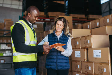 Happy warehouse manager smiling cheerfully while signing a bill of lading after receiving goods for shipment. Female freight forwarder importing merchandise from a consignor. - JLPPF01324