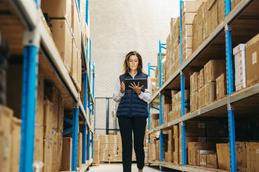 Warehouse worker using a warehouse management system on a digital tablet. Female logistics manager doing inventory control using smart warehousing technology. - JLPPF01347