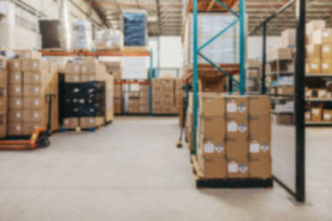 Defocused background of a fulfillment centre. Blurred view of package boxes stored on the shelves of a large distribution warehouse. - JLPPF01382