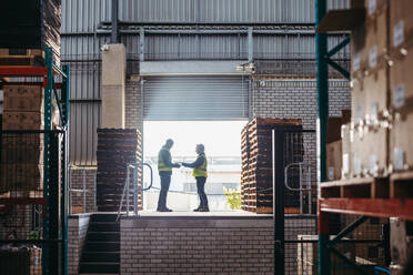 Happy logistics partners signing a dock receipt while standing at the loading dock of a warehouse. Freight forwarder confirming the delivery of a shipment from a consignor. - JLPPF01438