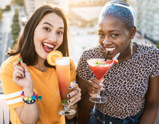 Von oben stilvolle multiethnische lesbische Frauen, die im Sommer kalte erfrischende Cocktails trinken - ADSF39196