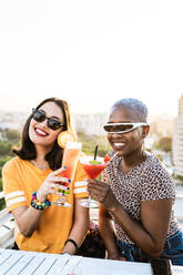 From above stylish multiethnic lesbian females drinking cold refreshing cocktails in summer - ADSF39199