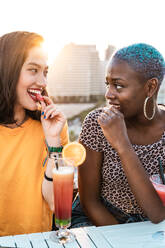 Stylish multiethnic lesbian females drinking cold refreshing cocktails in summer - ADSF39207