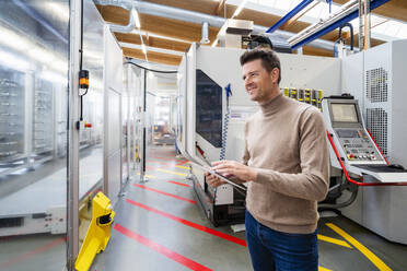 Lächelnder Geschäftsmann mit Tablet-PC in der Industrie - DIGF19011