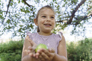 Cute girl holding green apple in park - TOF00138