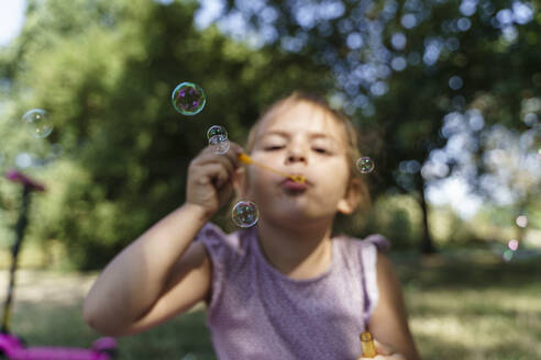 Girl blowing soap bubbles in park - TOF00141