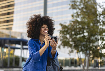 Glückliche Afro-Frau beim Fotografieren durch die Kamera - JCCMF07393