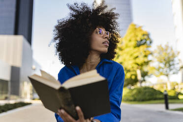 Frau mit Afrofrisur und Brille hält Buch - JCCMF07410