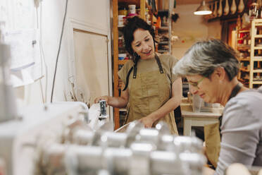 Lächelnder Unternehmer im Gespräch mit einem Kollegen in der Keramikwerkstatt - MRRF02457