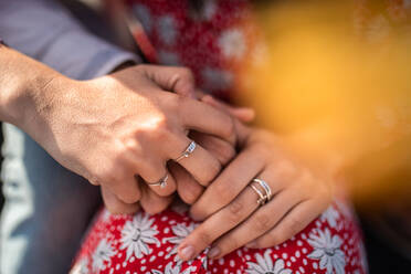 Crop unrecognizable loving couple in stylish clothes hugging and holding hands on sunny day - ADSF39253