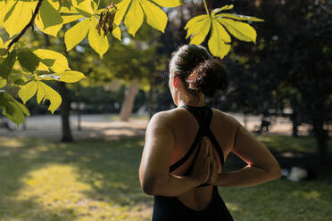 Fitness instructor doing stretching exercise in park - MRRF02483