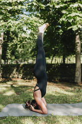 Yoga teacher practicing Salamba Shirshasana posture in park - MRRF02488