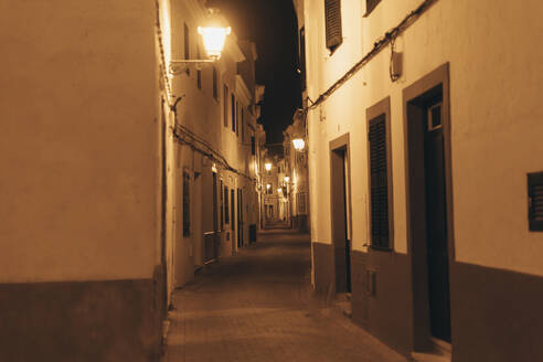 Spanien, Balearische Inseln, Ciutadella de Menorca, Leere beleuchtete Gasse bei Nacht - EGHF00553