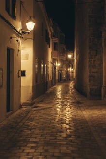 Spanien, Balearische Inseln, Ciutadella de Menorca, Leere beleuchtete Gasse bei Nacht - EGHF00554