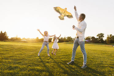 Vater und Tochter genießen das Drachensteigenlassen im Park bei Sonnenuntergang - SIF00498