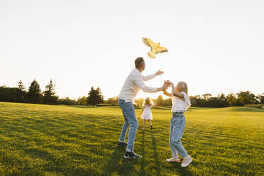 Father and daughter flying kite together in park - SIF00499