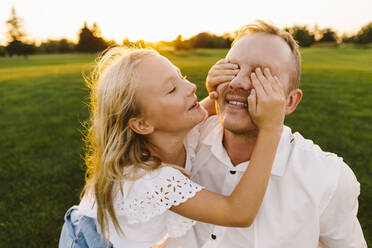 Happy daughter covering father's eyes in park - SIF00507