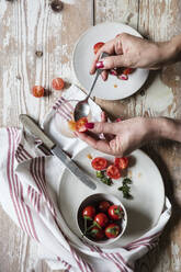 Hands of woman removing seeds from fresh homegrown tomatoes - EVGF04095