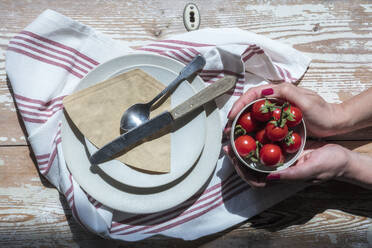 Teller und Hände einer Frau, die eine Schüssel mit selbstgezogenen Tomaten hält - EVGF04097