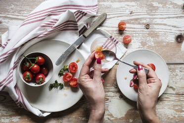 Hands of woman removing seeds from fresh homegrown tomatoes - EVGF04102