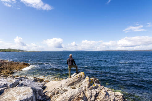 Mann steht auf einem Felsen am See Loch Ailort - SMAF02237