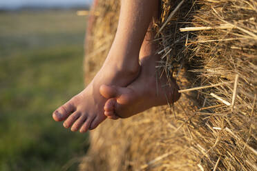 Legs of girl crossed at ankle on haystack - NJAF00009