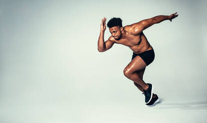 Studio shot of fit young man running over grey background. African american male model with muscular body. - JLPSF00003