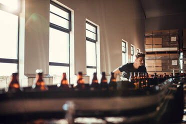 Junger Mann, der die Herstellung von Bier in einer Brauerei überwacht. Mann, der in einer Fabrik zur Herstellung von Alkohol arbeitet. - JLPSF00086