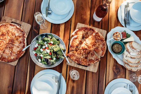 Draufsicht auf Essen und Getränke auf Holztisch für Einweihungsparty. Tisch im Freien mit leckerem Essen und Trinken zum Abendessen. - JLPSF00130