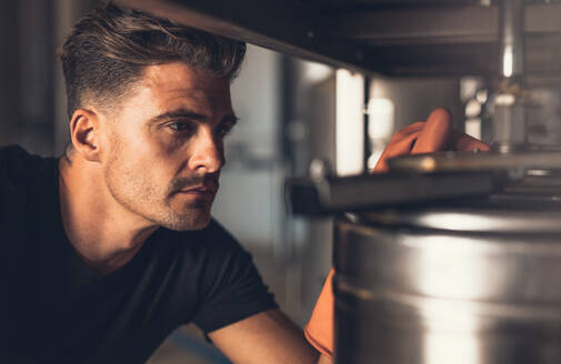 Close up of brewer working at brewery. Male brewer working with brewery equipment. - JLPSF00143