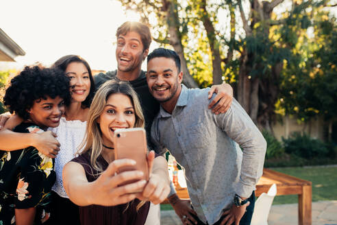 Junge Freunde, die zusammen feiern und ein Selfie mit ihrem Handy machen. Eine Gruppe von Menschen auf einer Einweihungsparty macht ein Selfie. - JLPSF00163