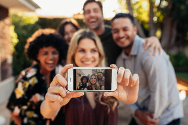 Glückliche junge Freunde, die sich auf einer Party amüsieren und ein Selfie machen, Fokus auf das Handy in der Hand einer Frau. - JLPSF00167