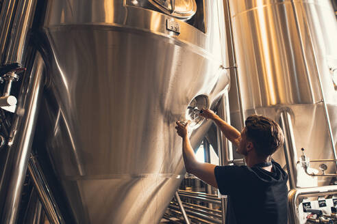 Junger Mann bei der Arbeit in einer Bierfabrik. Brauer bei der Arbeit mit Industrieanlagen in der Brauerei. - JLPSF00168