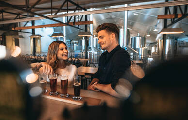 Junger Mann und Frau an der Bar mit verschiedenen Biersorten. Pärchen an Brauereibar und Bierverkostung. - JLPSF00182