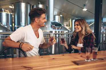 Ein Paar in einer Brauerei, das auf ein Bier anstößt. Ein junger Mann und eine Frau probieren verschiedene Sorten von Craft-Bieren. - JLPSF00239