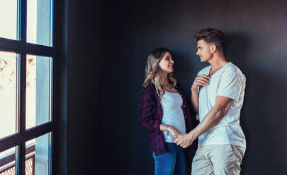 Portrait of loving young couple looking at each other. Man and woman in love standing together indoors. - JLPSF00240