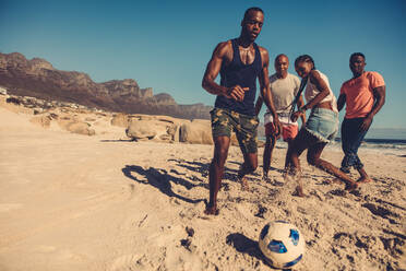 Junge Leute spielen zusammen Fußball am sandigen Meeresufer. Eine Gruppe von Menschen genießt ein Fußballspiel am Strand. - JLPSF00244