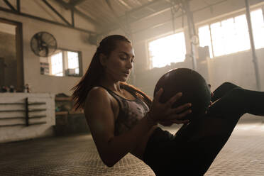 Weibliches Fitnessmodel beim Training mit Medizinball im Fitnessstudio. Junge Frau beim Workout mit Fitnessball. - JLPSF00260