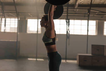 Fit young woman working out with heavy weights at cross training gym. Woman performing deadlift with barbell. - JLPSF00261