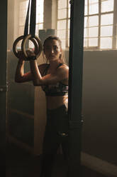 Fitte Frau trainiert an den Ringen im Fitnessstudio. Junge Frau trainiert im Fitnessstudio. - JLPSF00292