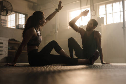 Fitness-Mann und Frau, die sich gegenseitig ein High-Five nach dem Training in der Turnhalle. Fit Paar High-Five nach dem Training im Fitness-Studio. - JLPSF00299