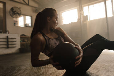 Fitness-Frau trainiert im Fitnessstudio mit Medizinball. Sportlerin dehnt sich mit Medizinball im Fitnessstudio. - JLPSF00314