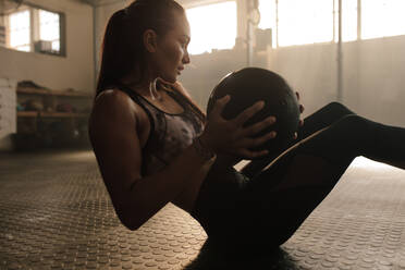 Determined fitness woman exercising with pilates ball at healthclub. Female doing workout using medicine ball. - JLPSF00315