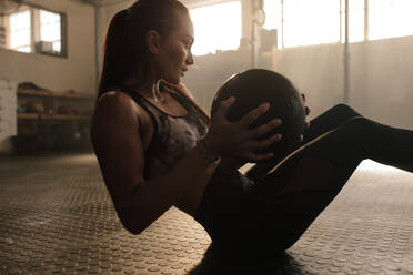 Entschlossene Fitness-Frau, die mit einem Pilates-Ball im Fitnessstudio trainiert. Frau macht Training mit Medizinball. - JLPSF00315