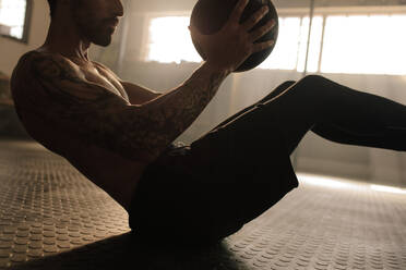 Muskulöser Mann trainiert mit Medizinball im Fitnessstudio. Junger Mann beim Workout mit Fitnessball. - JLPSF00316