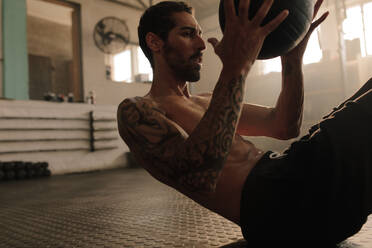 Starker und muskulöser Mann, der im Fitnessstudio mit einem Pilates-Ball trainiert. Männlich, der mit einem Medizinball trainiert. - JLPSF00321