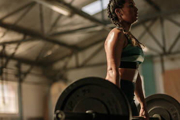 Muscular woman in gym doing heavy weight exercises. Young woman doing weight lifting at health club. - JLPSF00329