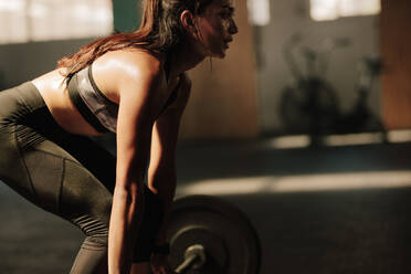 Woman with muscular body lifting heavy weights at gym. Fitness model performing weight lifting exercise at gym. - JLPSF00335