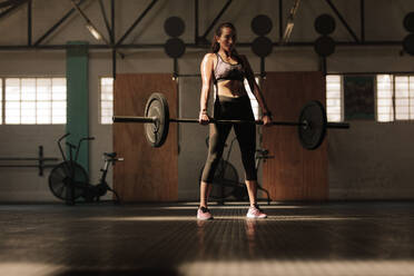 Fit junge weibliche Athletin hebt schwere Gewichte. Fitness-Modell Durchführung Gewicht Übung im Fitnessstudio. - JLPSF00337